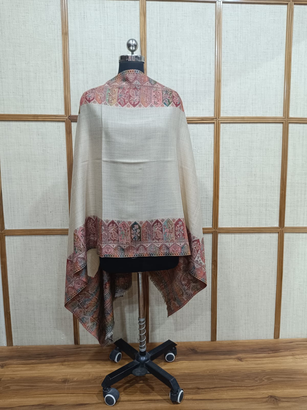Mannequin wearing a traditional outfit with intricate patterns against a wooden panel background